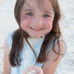 girl on the beaches of Destin Florida, holding shells