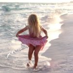 young girl dancing in the ocean waves at crystal beach in Destin Florida